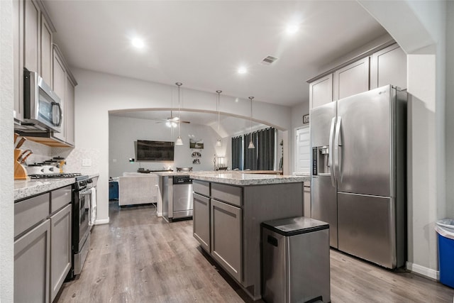 kitchen with stainless steel appliances, gray cabinets, light hardwood / wood-style flooring, and a center island