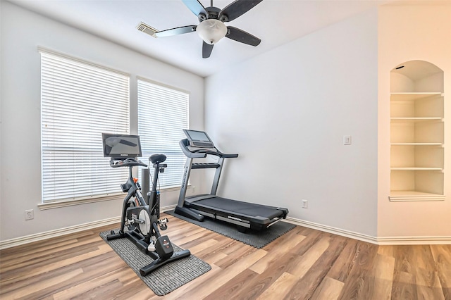 workout area with built in shelves, ceiling fan, and hardwood / wood-style flooring