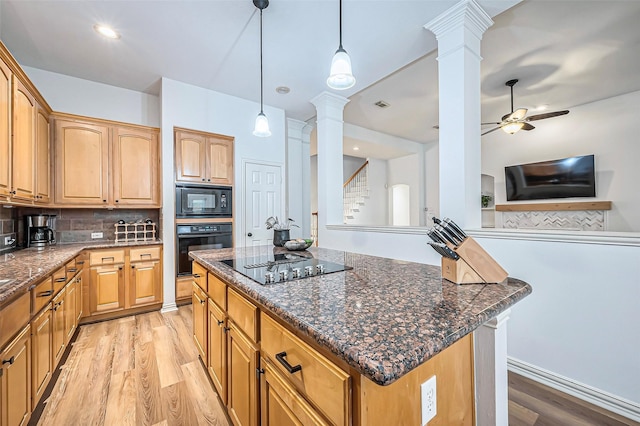 kitchen with ornate columns, black appliances, pendant lighting, light hardwood / wood-style flooring, and a kitchen island