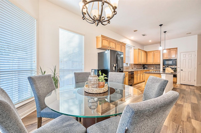 dining space with light hardwood / wood-style flooring and a chandelier