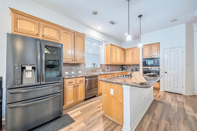 kitchen featuring backsplash, dark stone counters, hanging light fixtures, appliances with stainless steel finishes, and a kitchen island