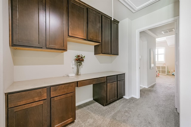 kitchen with crown molding, built in desk, vaulted ceiling, light carpet, and dark brown cabinets