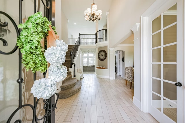 foyer with a notable chandelier, decorative columns, french doors, and a high ceiling