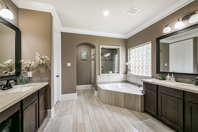 bathroom featuring crown molding, vanity, and a relaxing tiled tub