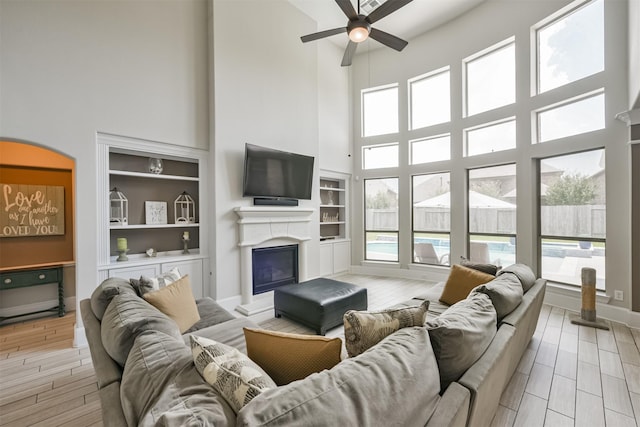 living room with a healthy amount of sunlight, built in features, and a towering ceiling