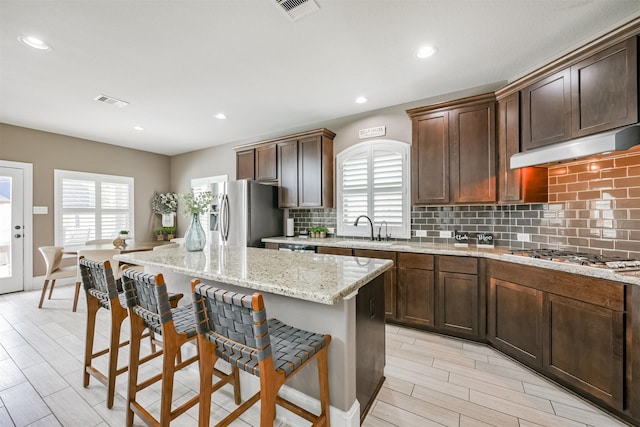 kitchen featuring a breakfast bar, stainless steel appliances, a center island, and sink