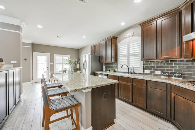 kitchen with stainless steel appliances, tasteful backsplash, a center island, and a kitchen breakfast bar