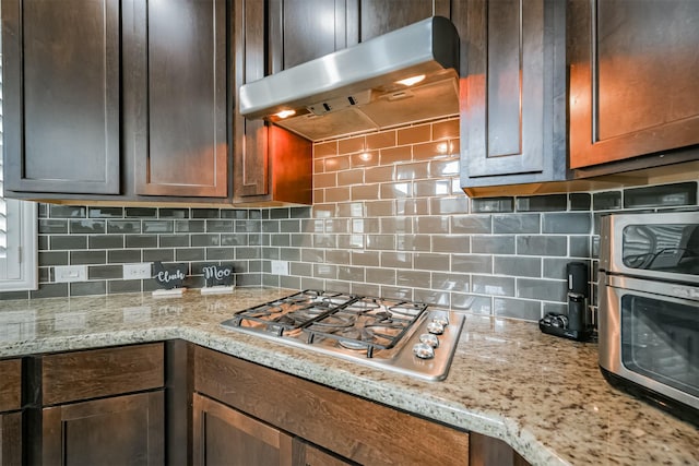 kitchen with tasteful backsplash, light stone countertops, and stainless steel gas cooktop