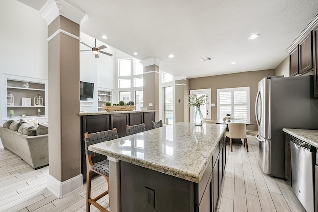 kitchen featuring light stone counters, a kitchen bar, a center island, and dark brown cabinets