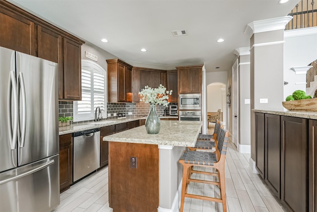 kitchen featuring a kitchen island, appliances with stainless steel finishes, light stone counters, and decorative backsplash