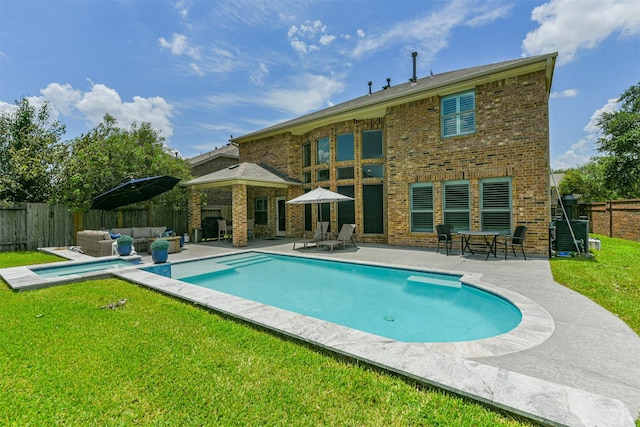 back of house featuring outdoor lounge area, a fenced in pool, a patio area, and a lawn