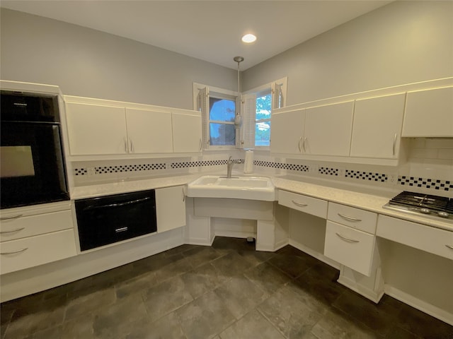 kitchen with oven, decorative light fixtures, light countertops, white cabinetry, and backsplash