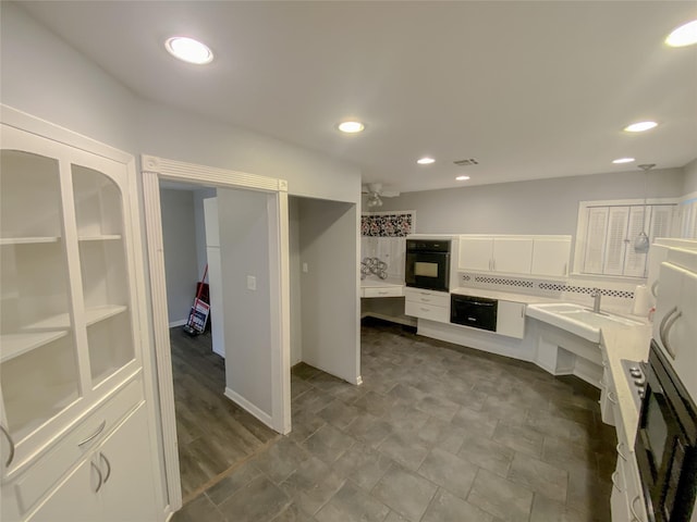 kitchen with recessed lighting, light countertops, visible vents, white cabinetry, and black oven