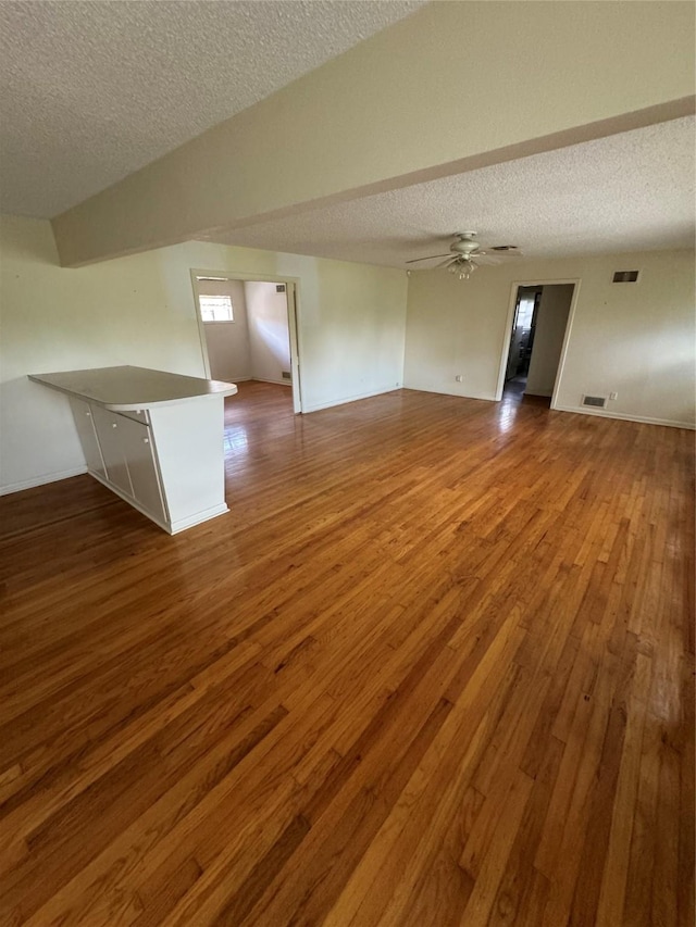 unfurnished living room featuring ceiling fan, hardwood / wood-style floors, and a textured ceiling