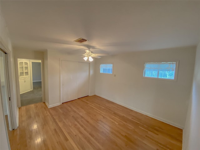 unfurnished bedroom with ceiling fan, visible vents, baseboards, a closet, and light wood finished floors