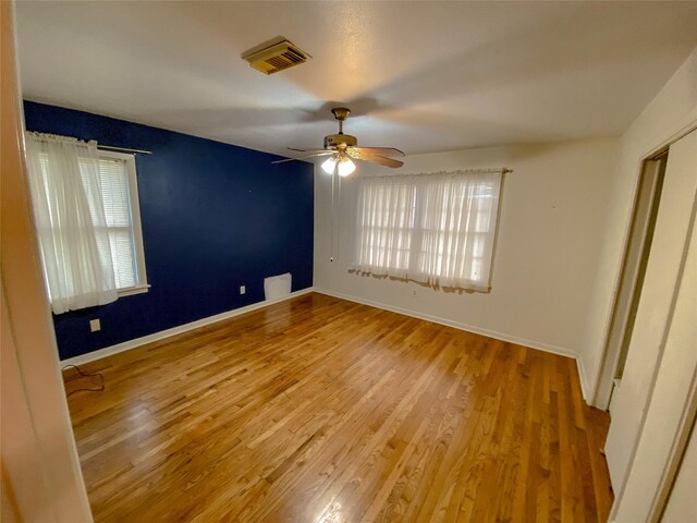 unfurnished bedroom featuring multiple windows, ceiling fan, and light wood-type flooring