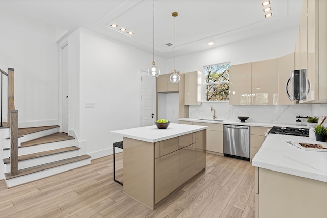 kitchen featuring sink, a center island, light hardwood / wood-style floors, decorative light fixtures, and appliances with stainless steel finishes