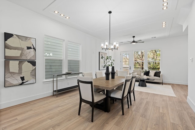 dining space with ceiling fan with notable chandelier and light hardwood / wood-style flooring