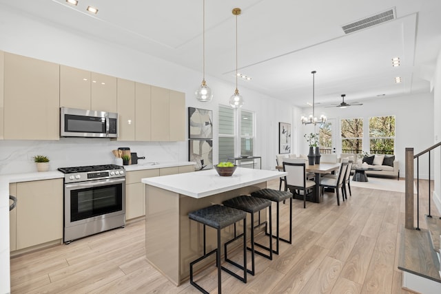 kitchen with appliances with stainless steel finishes, light hardwood / wood-style flooring, ceiling fan, and cream cabinets