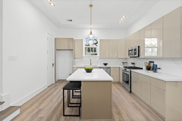 kitchen featuring light hardwood / wood-style flooring, a kitchen island, stainless steel appliances, and decorative light fixtures