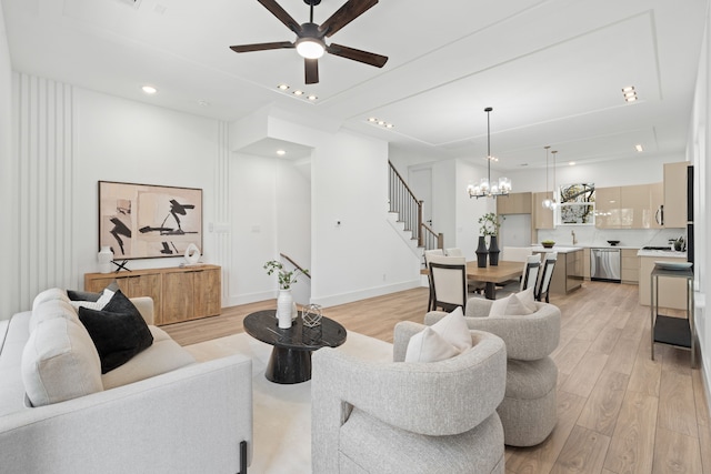 living room with light hardwood / wood-style flooring and ceiling fan with notable chandelier