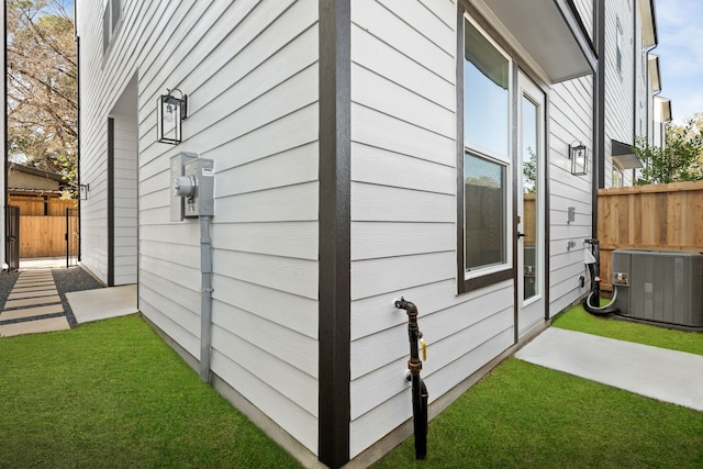 view of property exterior with central AC unit and a lawn