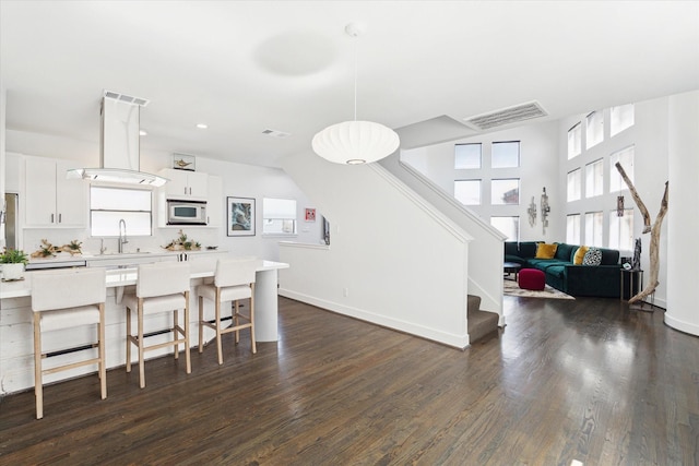 kitchen with a center island, white cabinets, sink, decorative light fixtures, and dark hardwood / wood-style flooring