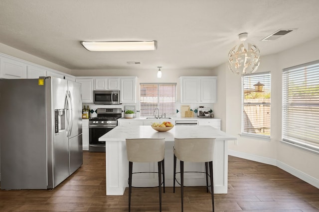 kitchen with decorative light fixtures, a center island, white cabinetry, and stainless steel appliances