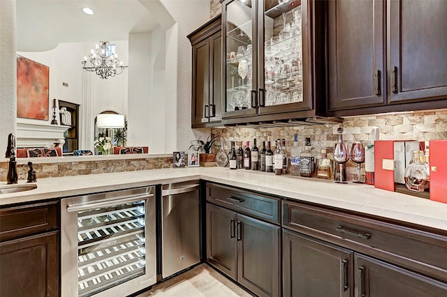 bar featuring dark brown cabinetry, decorative backsplash, sink, and beverage cooler