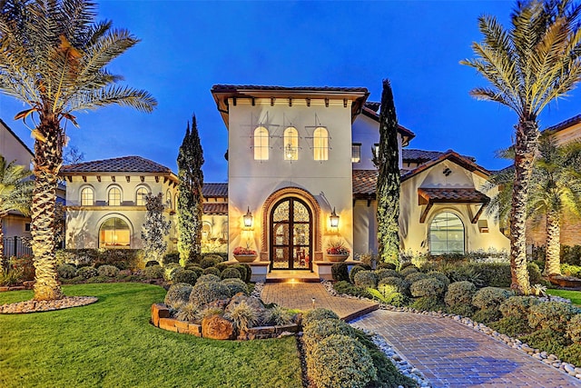 mediterranean / spanish house with a front lawn and french doors