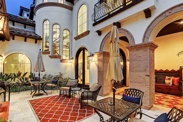 patio terrace at dusk featuring a balcony and french doors