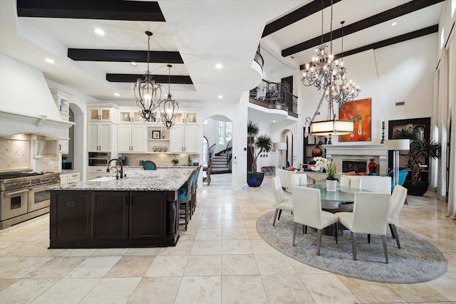 kitchen featuring decorative backsplash, decorative light fixtures, range with two ovens, and a spacious island