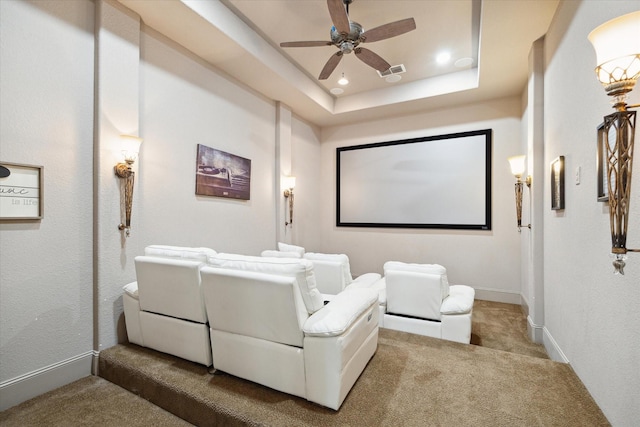 carpeted home theater with ceiling fan and a raised ceiling