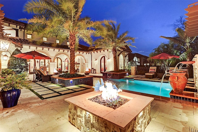 view of pool featuring pool water feature, a patio, and an outdoor fire pit