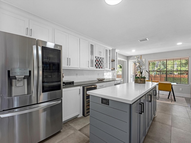 kitchen featuring stainless steel fridge, gray cabinetry, beverage cooler, a center island, and white cabinetry