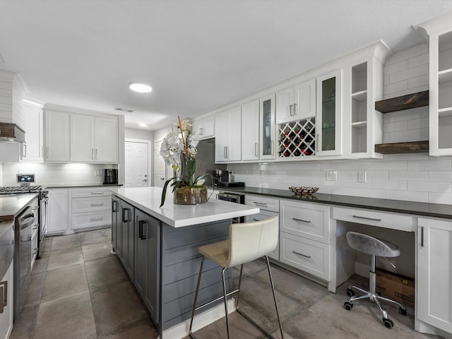 kitchen with gray cabinetry, built in desk, white cabinets, a kitchen island, and a breakfast bar area