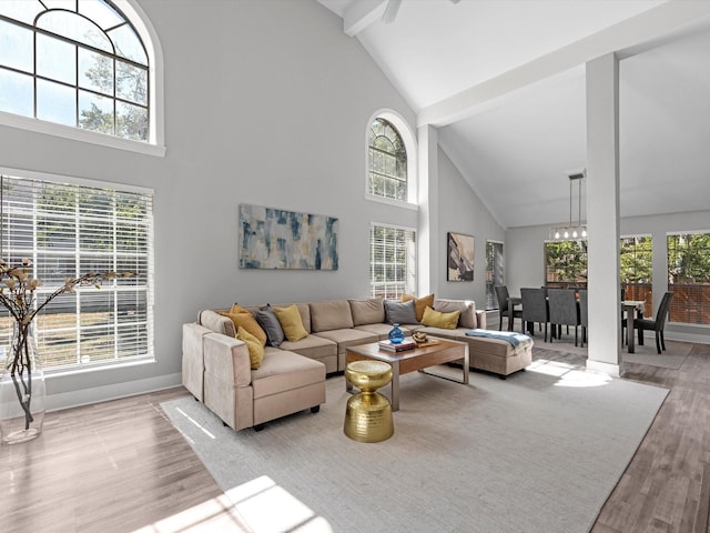 living room with beam ceiling, a towering ceiling, and light hardwood / wood-style flooring