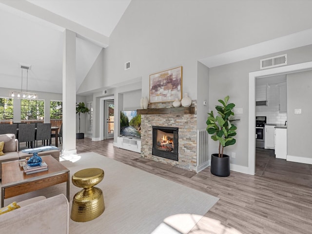 living room featuring a stone fireplace, wood-type flooring, and high vaulted ceiling