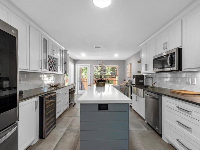 kitchen with white cabinetry, a center island, wine cooler, decorative backsplash, and appliances with stainless steel finishes