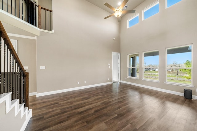 unfurnished living room featuring dark wood finished floors, stairway, and baseboards