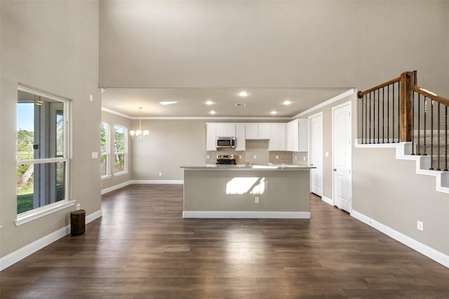 kitchen with white cabinets, a center island with sink, ornamental molding, tasteful backsplash, and stainless steel appliances