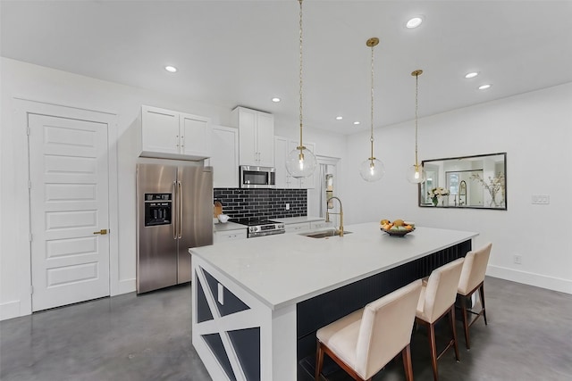 kitchen with a center island with sink, sink, hanging light fixtures, white cabinetry, and stainless steel appliances