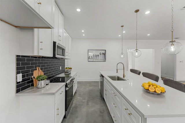 kitchen with white cabinetry, sink, stainless steel appliances, decorative light fixtures, and a kitchen island with sink