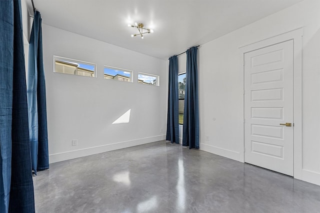 unfurnished room featuring concrete flooring and an inviting chandelier