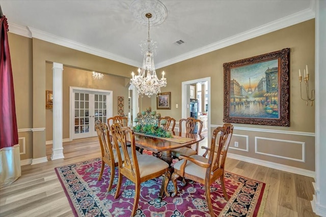 dining room with decorative columns, ornamental molding, and light wood-type flooring