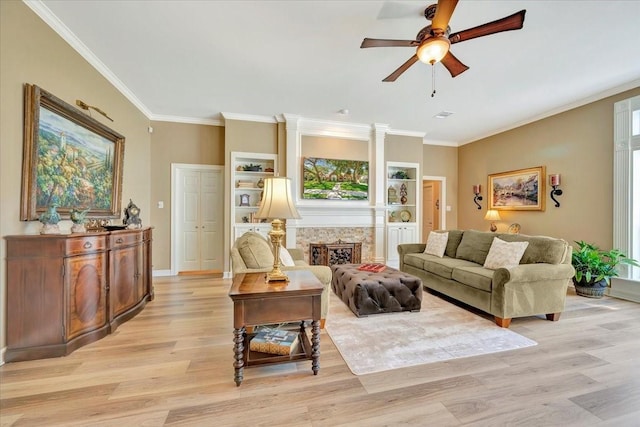 living room with ceiling fan, crown molding, a high end fireplace, and light hardwood / wood-style flooring