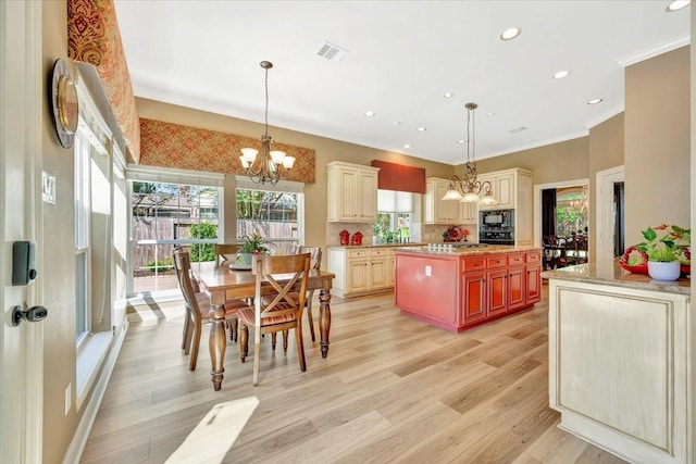 kitchen featuring black appliances, decorative light fixtures, a center island, and a chandelier