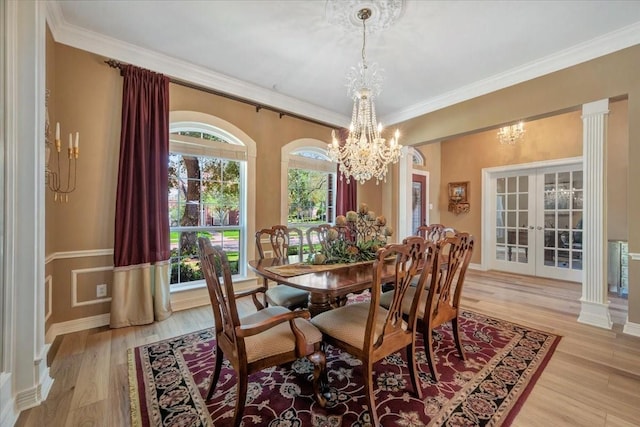 dining space featuring decorative columns, french doors, crown molding, light hardwood / wood-style floors, and a chandelier