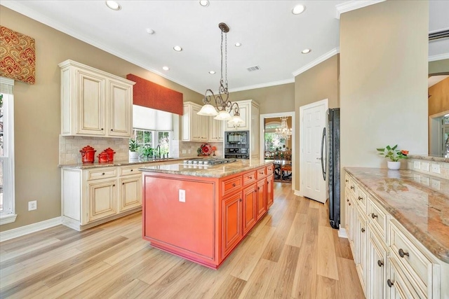 kitchen featuring black appliances, sink, hanging light fixtures, and cream cabinets