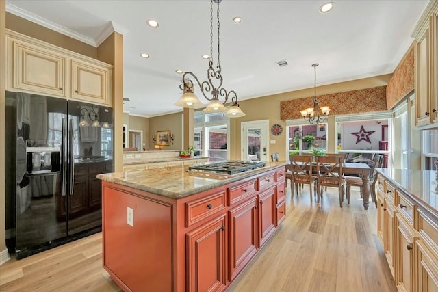 kitchen with black refrigerator with ice dispenser, pendant lighting, a chandelier, a kitchen island, and stainless steel gas stovetop